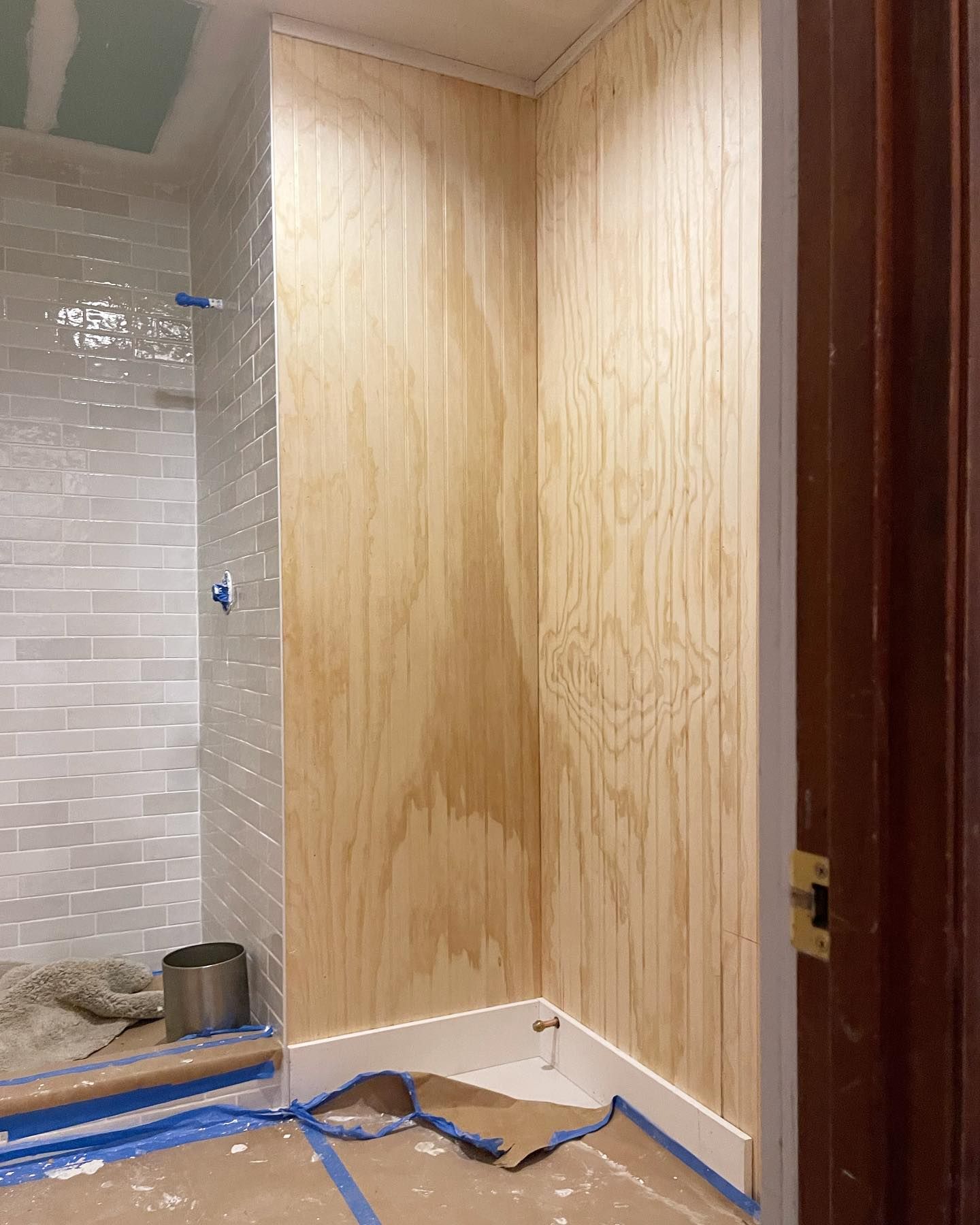 A bathroom with white tiles and wood paneling is being remodeled.