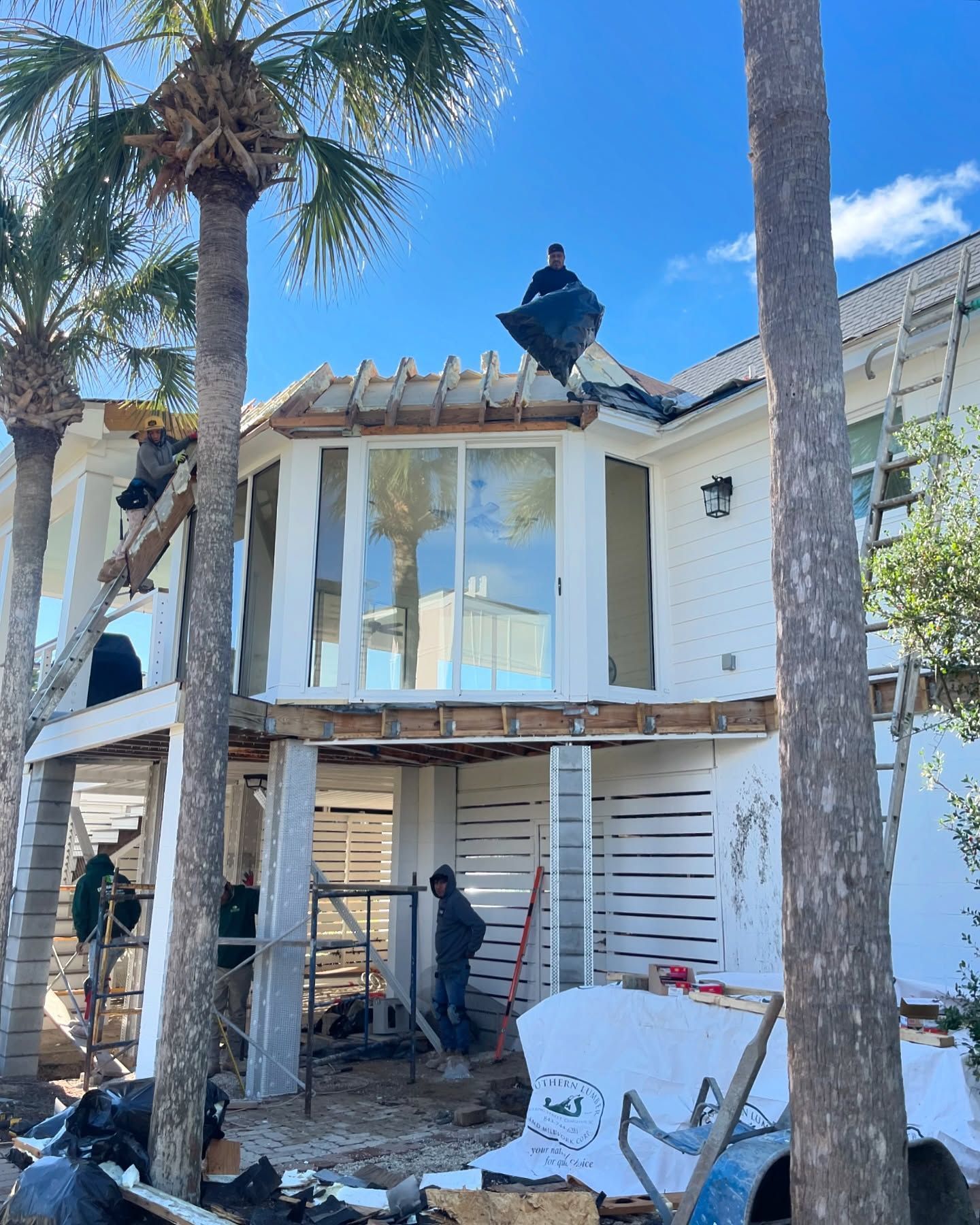 A man is standing on the roof of a house under construction.