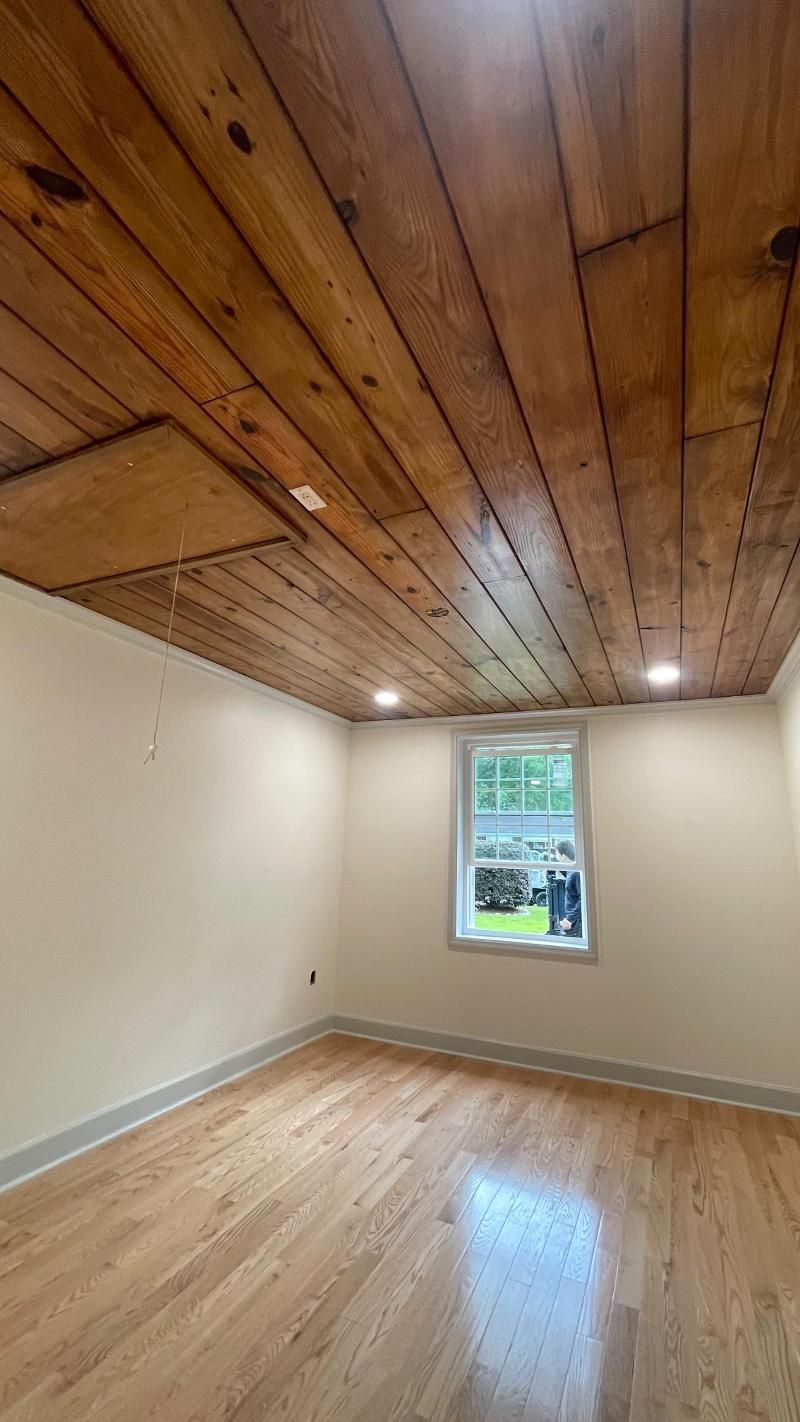 An empty room with a wooden ceiling and hardwood floors.