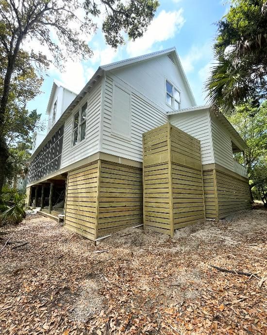 A large white house with a wooden fence around it is surrounded by trees.