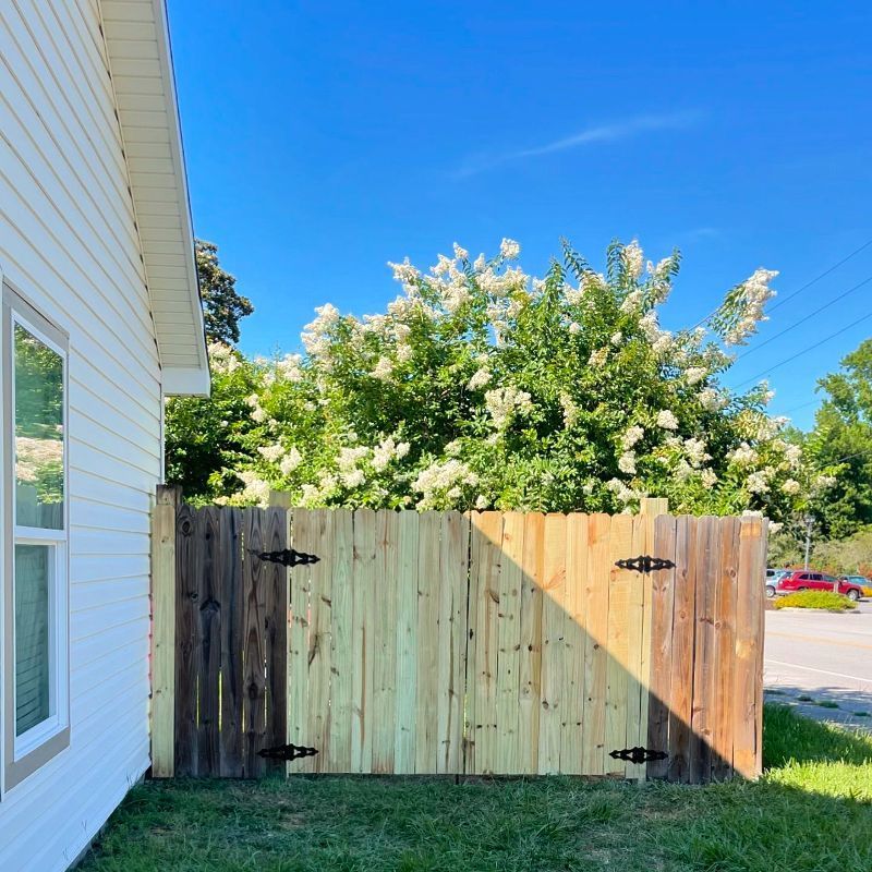 A wooden fence is sitting next to a white house.