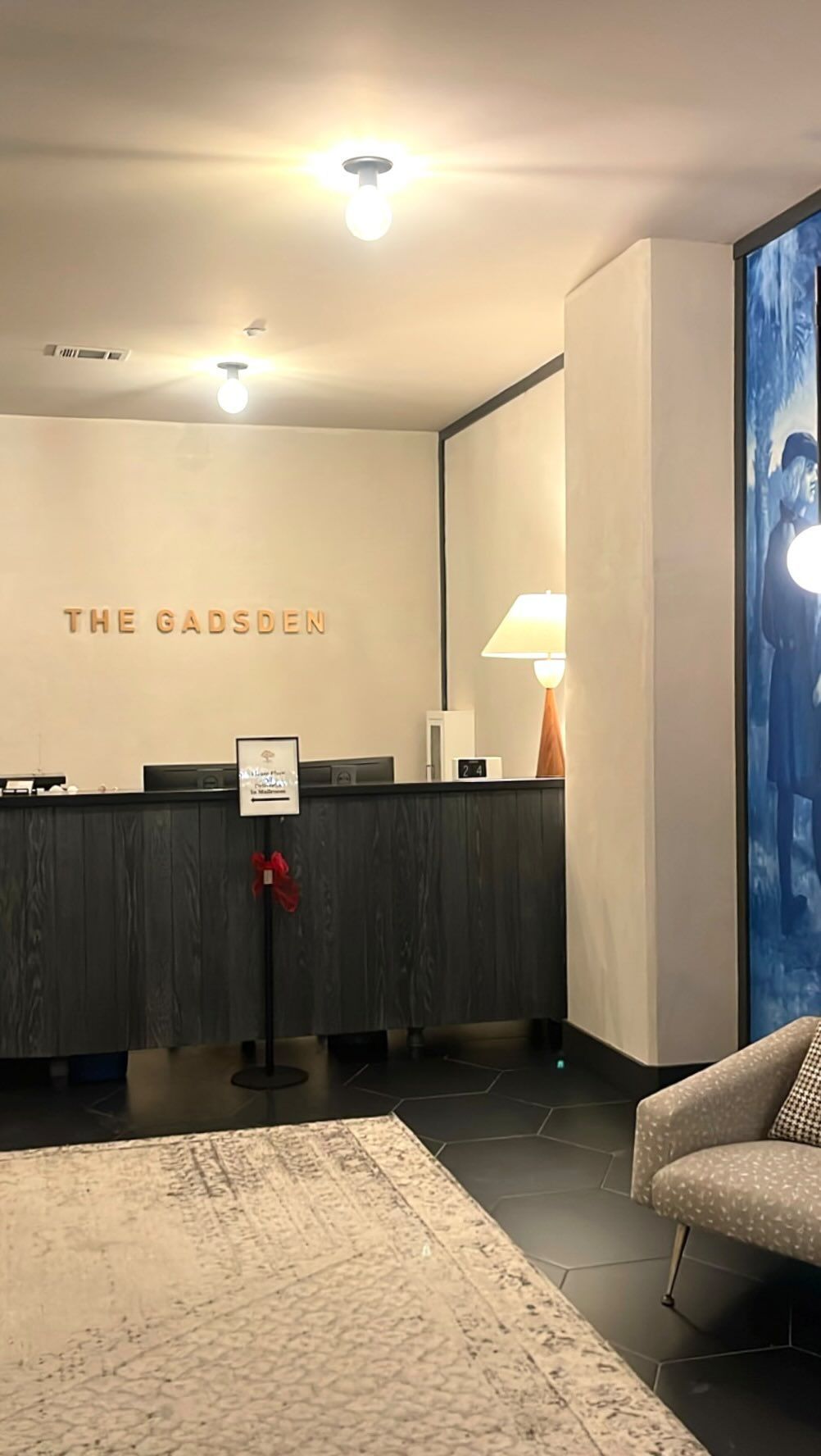 A hotel lobby with a reception desk and a chair.
