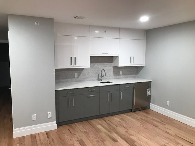 a kitchen with gray cabinets and white counter tops and a sink .