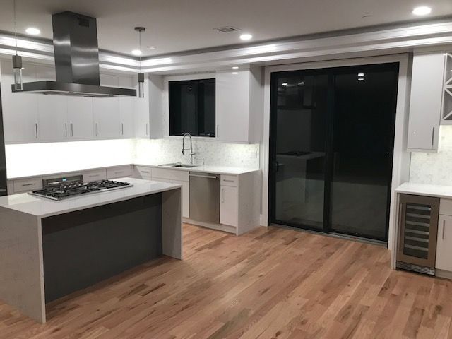 a kitchen with white cabinets and hardwood floors and a stove top oven .