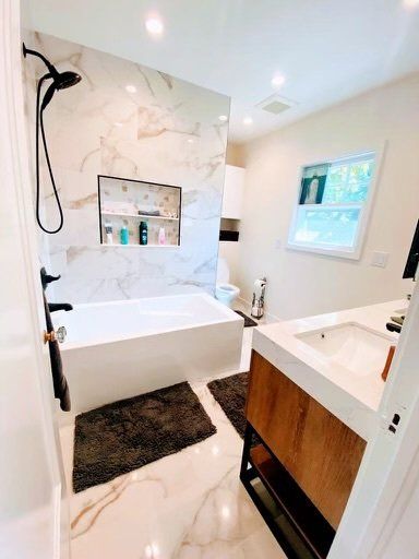 A bathroom with a bathtub , sink , and shower.