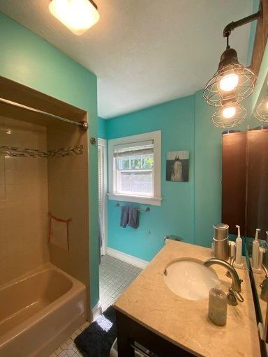 A bathroom with a sink , tub , shower and mirror.
