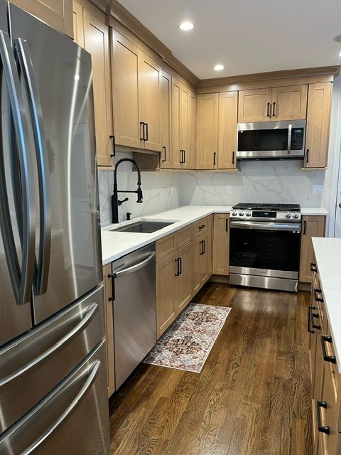 Stainless steel kitchen appliances with white countertops and wood cabinetry