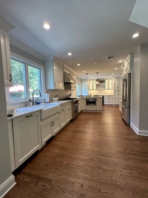 A kitchen with white cabinets , hardwood floors , and stainless steel appliances.