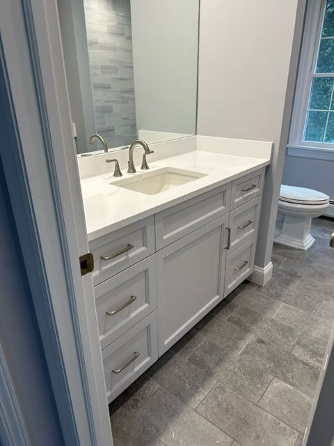 A bathroom with a sink , toilet and mirror.
