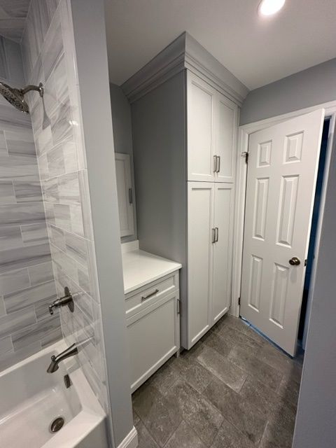 A bathroom with a tub , sink , cabinets and a door.
