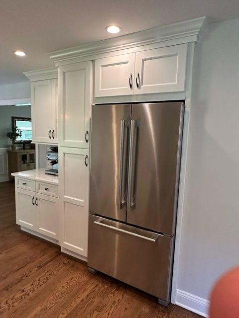 A kitchen with white cabinets and a stainless steel refrigerator.
