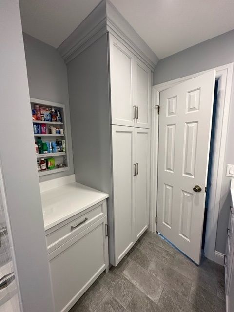 A laundry room with white cabinets and a door