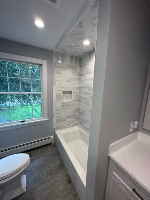 A bathroom with a toilet a bathtub and a window