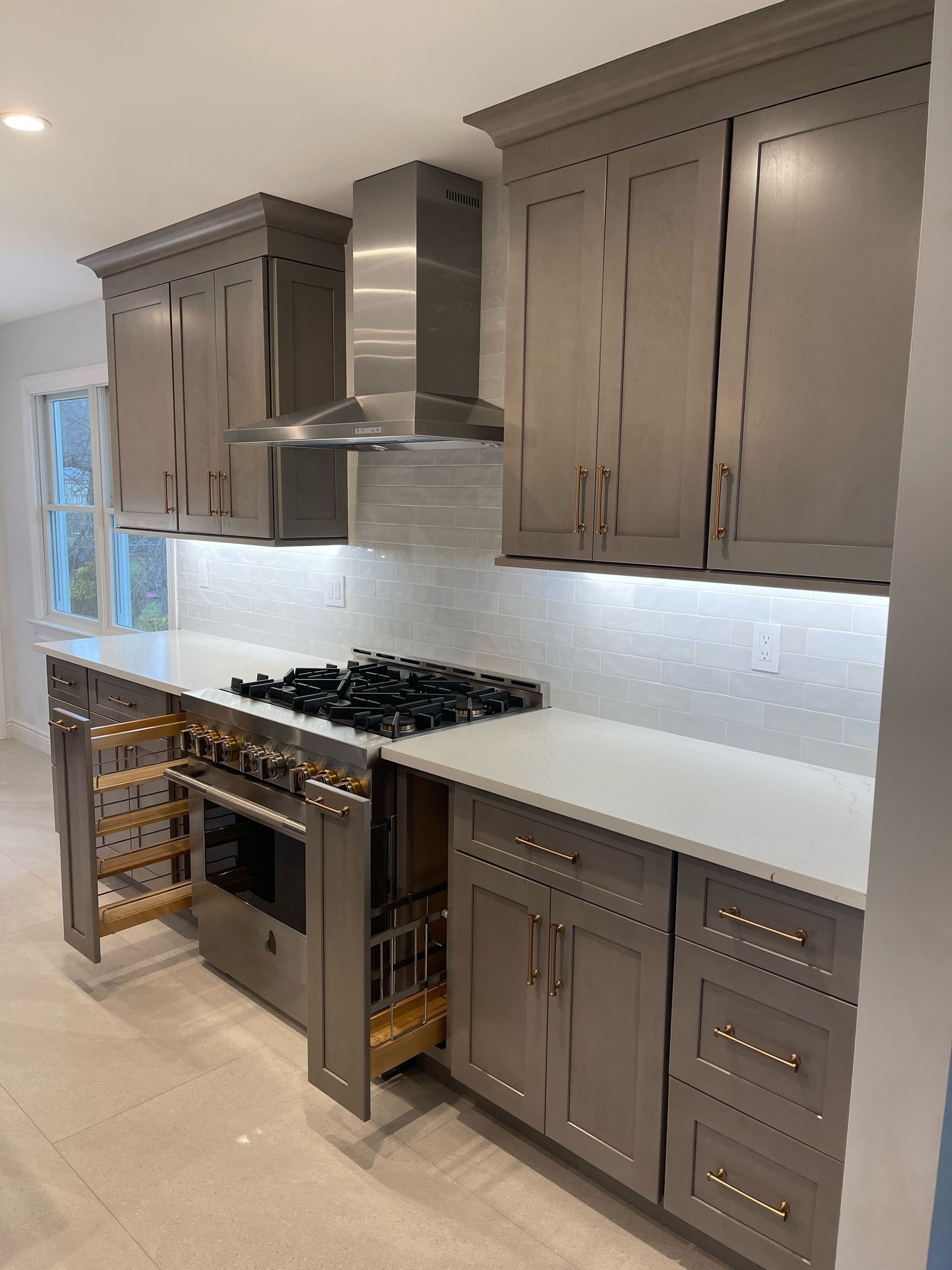 A kitchen with stainless steel appliances and gray cabinets.