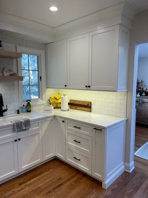 A kitchen with white cabinets and hardwood floors