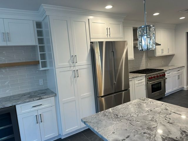 A kitchen with white cabinets , stainless steel appliances and granite counter tops.