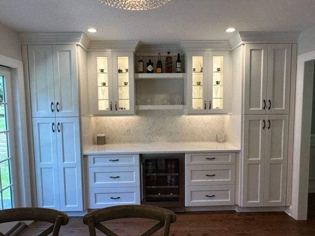 A kitchen with white cabinets and a refrigerator.