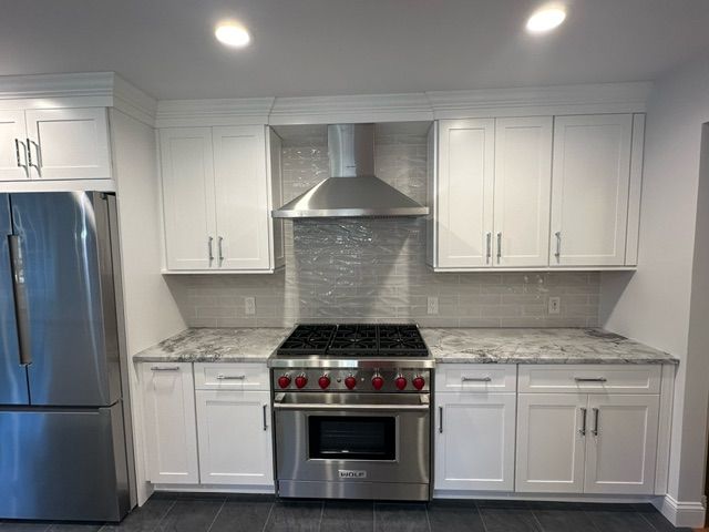 A kitchen with stainless steel appliances and white cabinets.