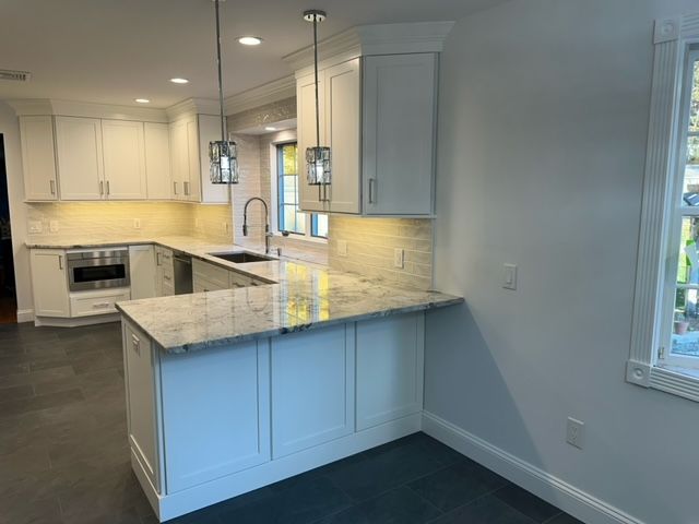 A kitchen with white cabinets , granite counter tops , a sink , and a window.