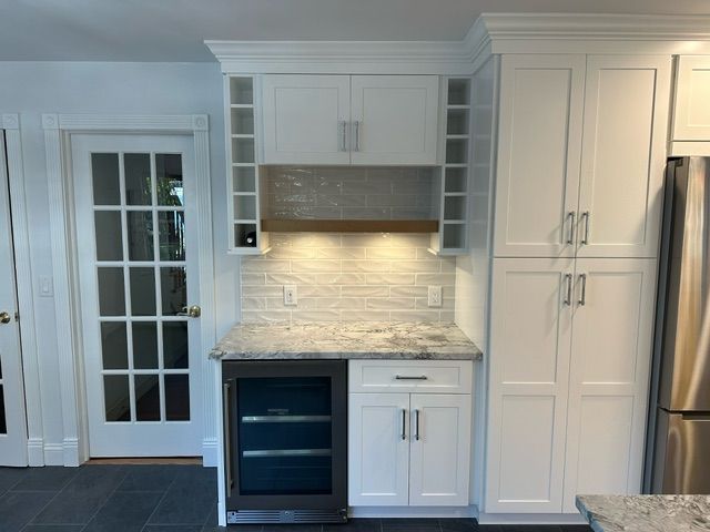 A kitchen with white cabinets and a stainless steel refrigerator
