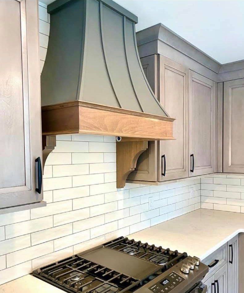 A kitchen with a stove top oven and a hood above it.