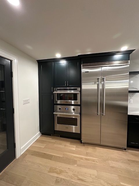 A kitchen with stainless steel appliances and black cabinets.