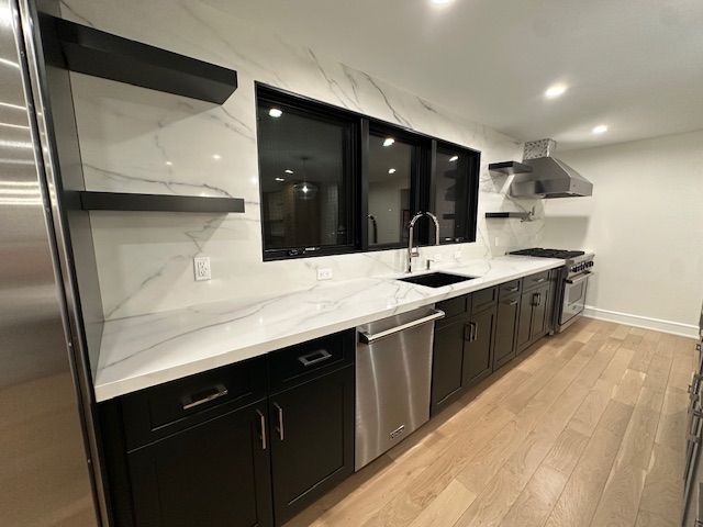 A kitchen with black cabinets and stainless steel appliances
