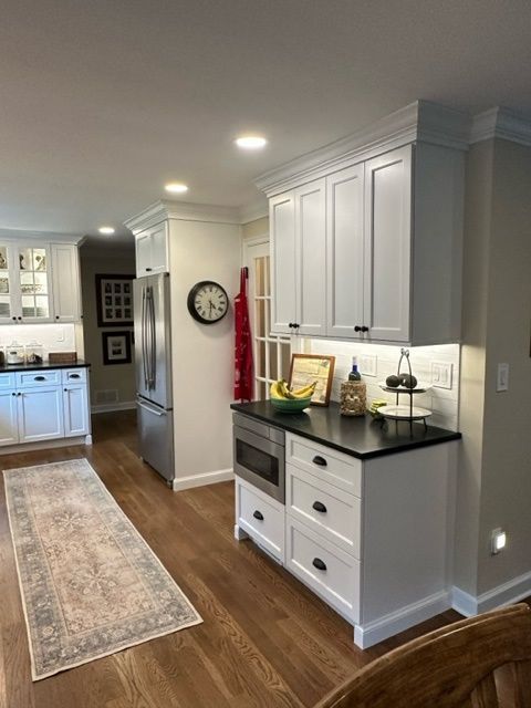A kitchen with white cabinets and a clock on the wall