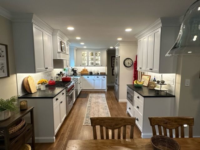 A kitchen with white cabinets and black counter tops