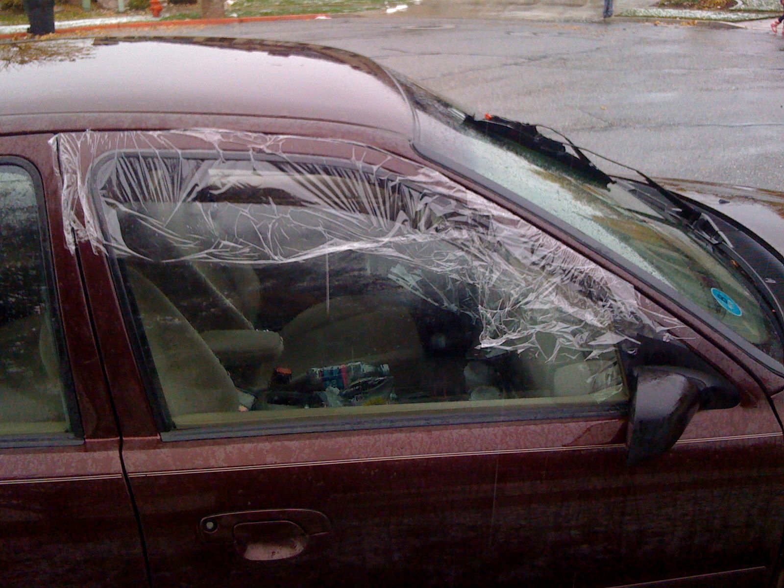 a car with a broken windshield is parked on the side of the road