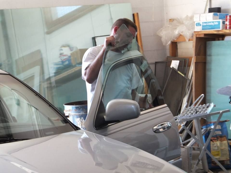 a man is working on a car windshield in a garage