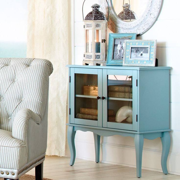 a blue cabinet with glass doors sits in a living room next to a chair