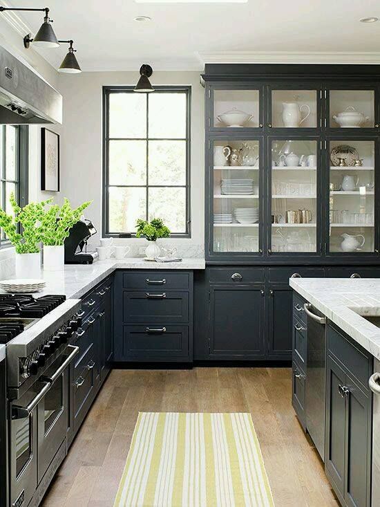 a kitchen with black cabinets, white counter tops, stainless steel appliances, a stove and a window