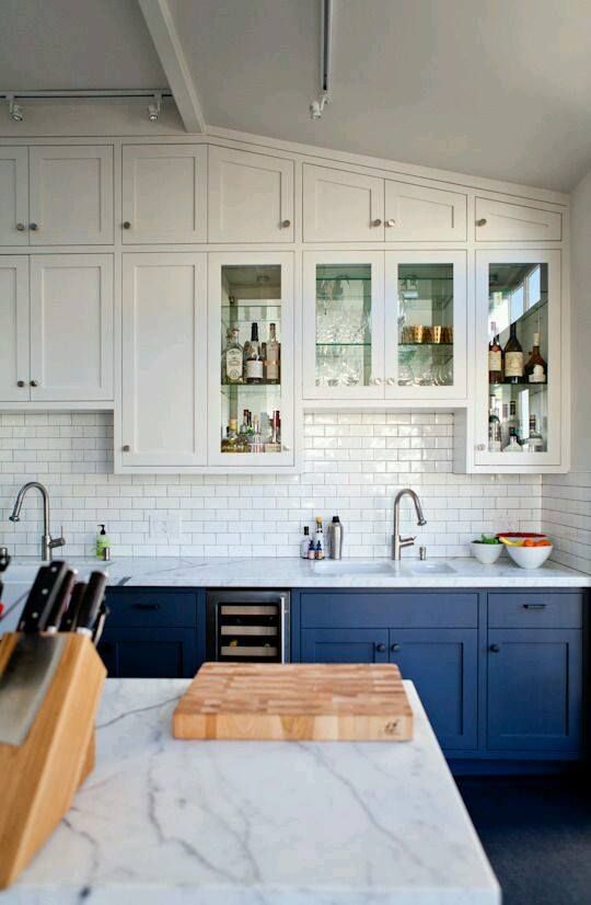 a kitchen with blue cabinets and white cabinets has a cutting board on the counter