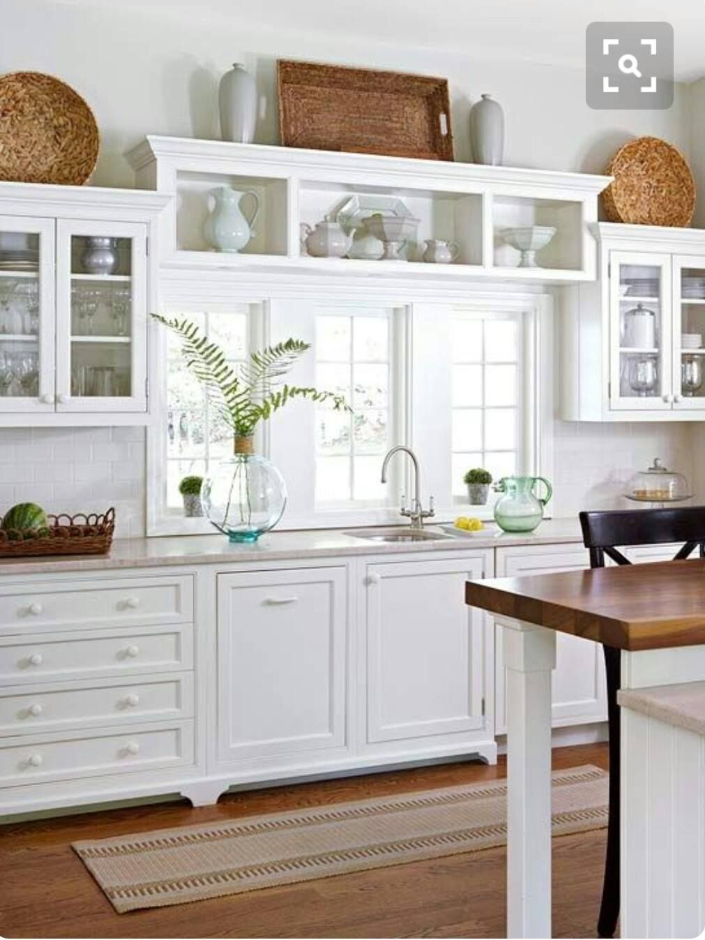 a kitchen with white cabinets and a wooden table