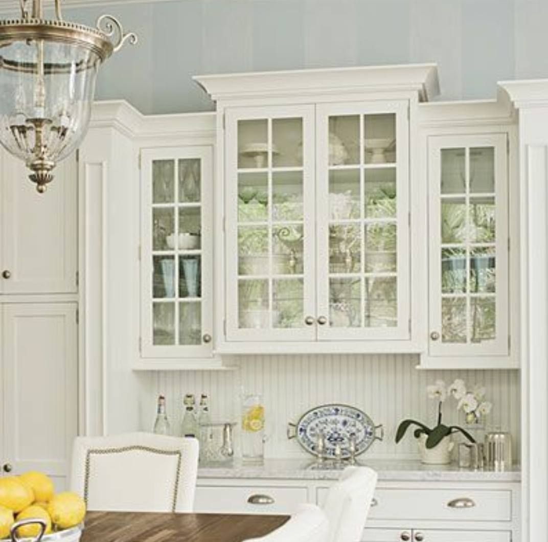 a kitchen with white cabinets and glass doors