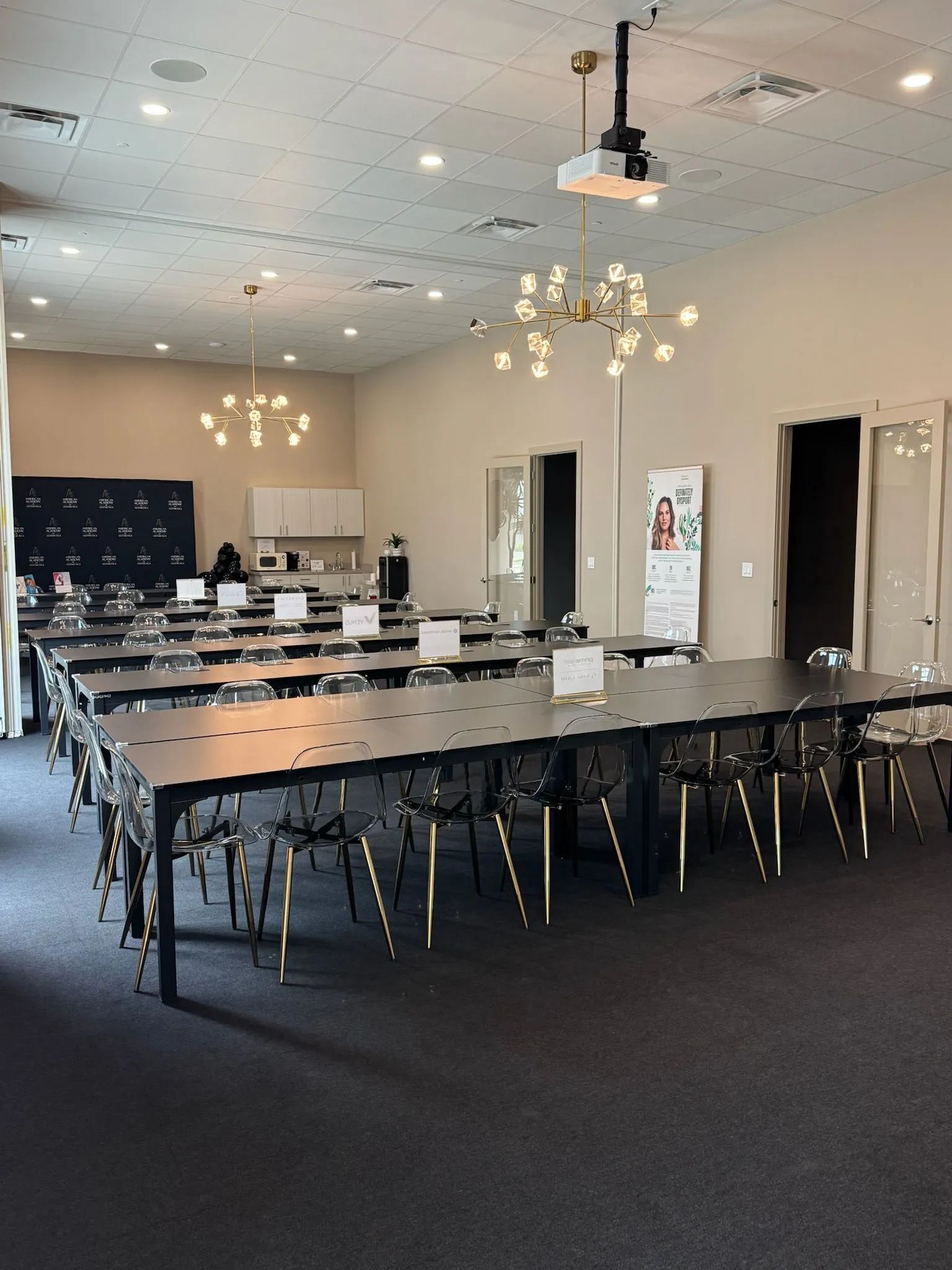 Empty conference room with long tables, chairs, chandeliers, and a carpeted floor