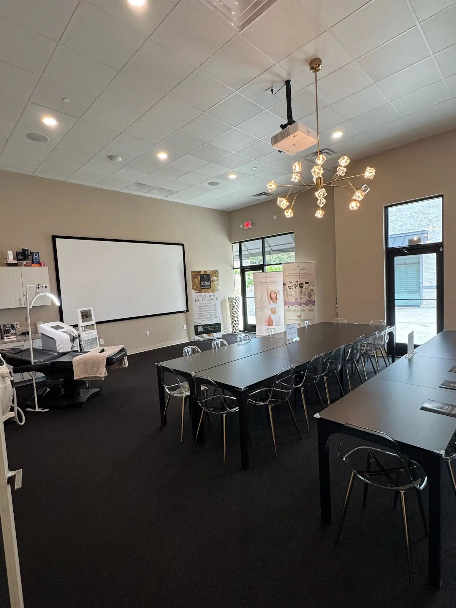 Conference room with long table, chairs, projector screen, and chandelier lighting