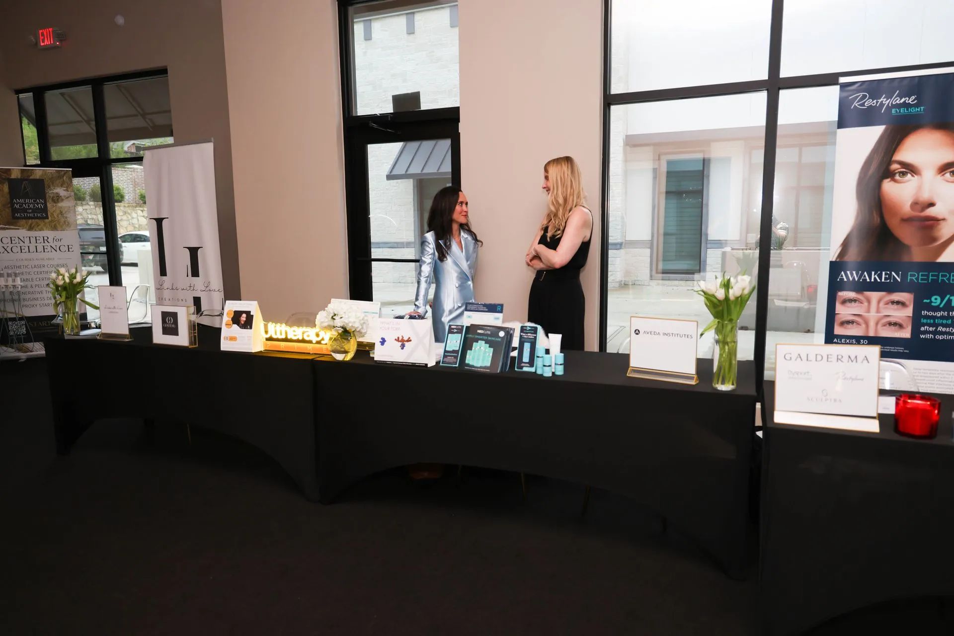 Vendor booth with black tablecloth, product displays, and two people standing inside a bright storefront entrance