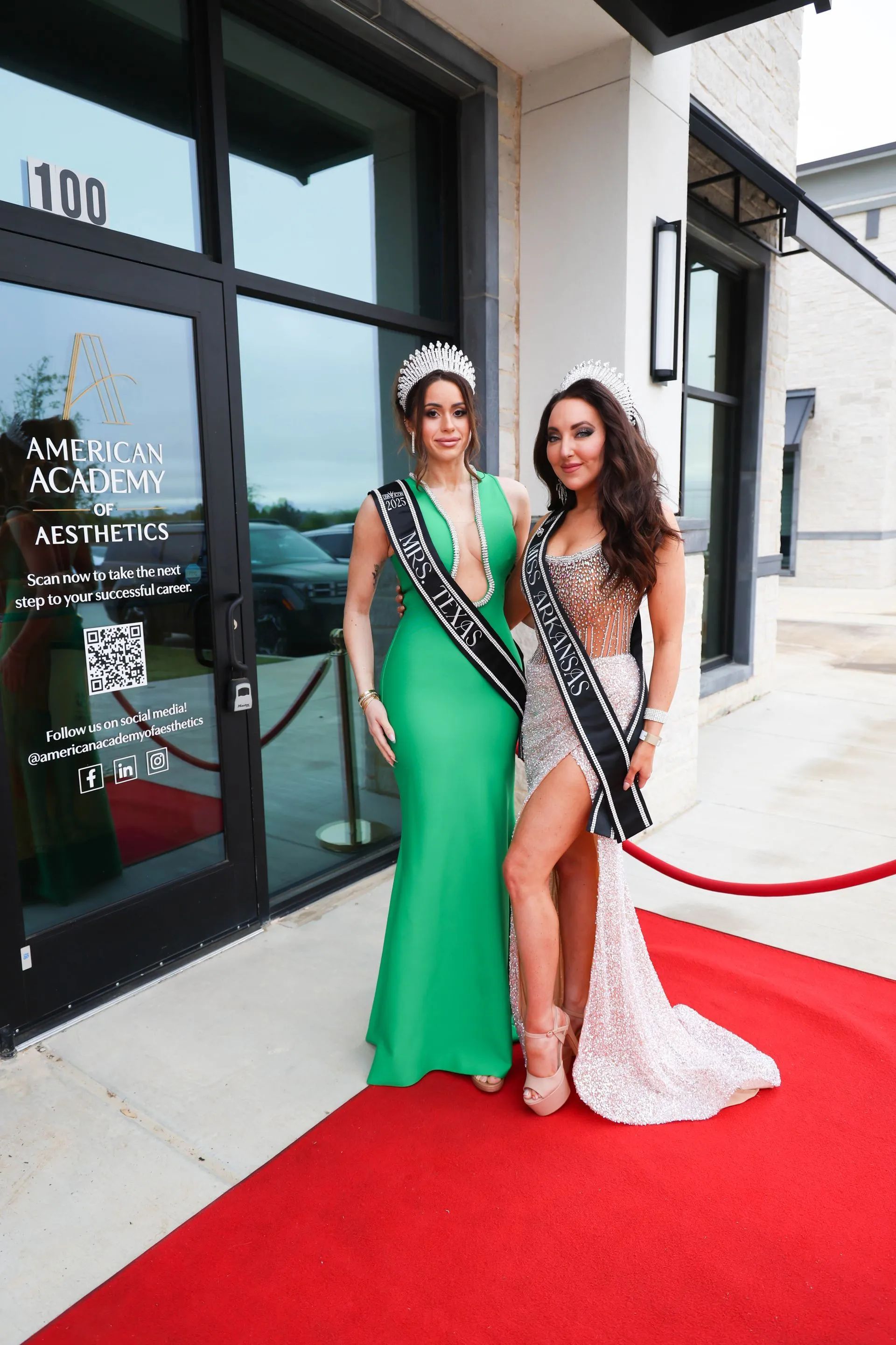 Two women in green and white gowns posing on a red carpet outside a building
