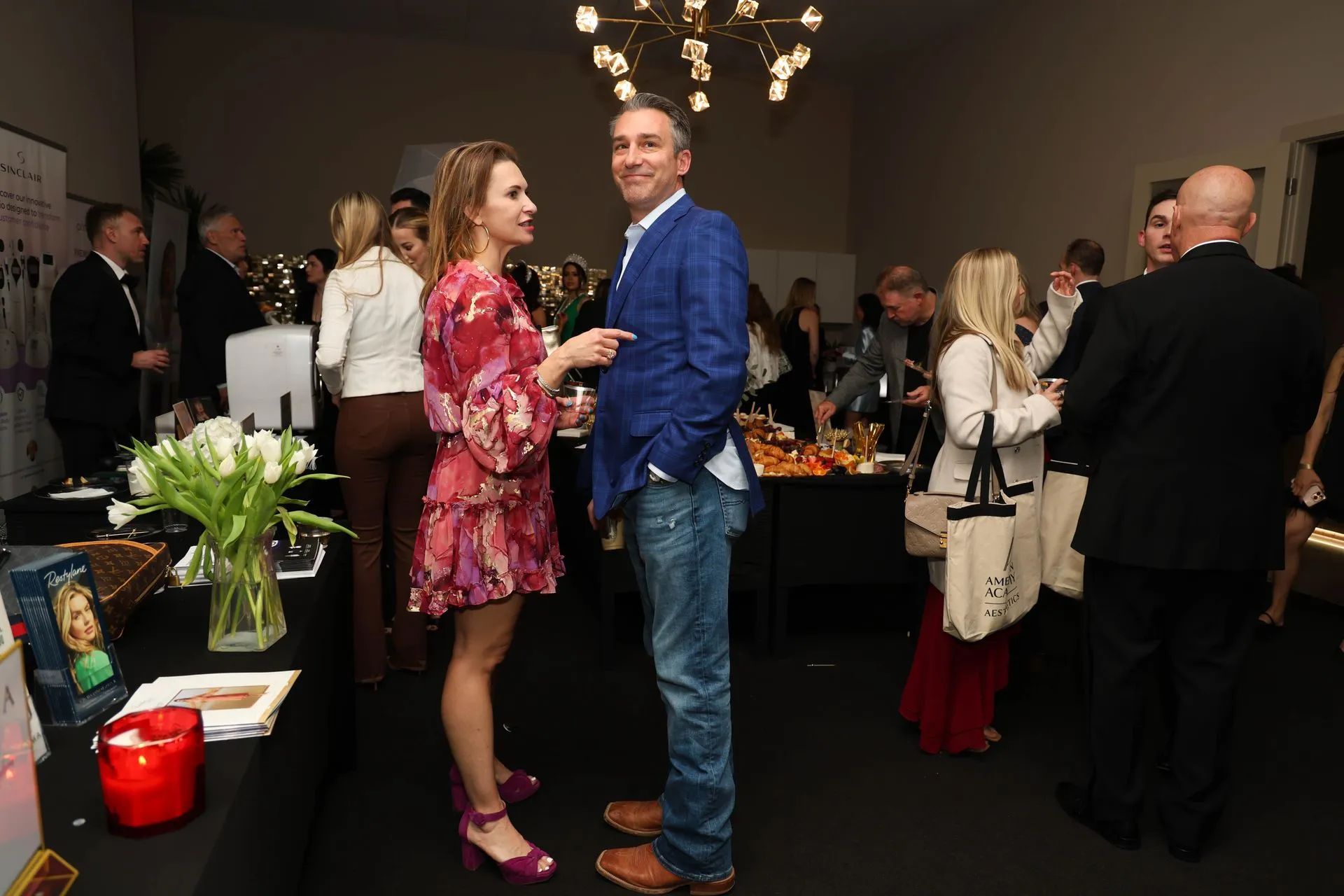 People mingling at a social event, with a couple standing together in the foreground.