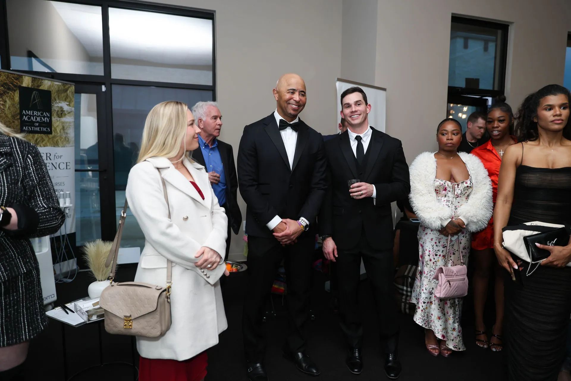 Group of people standing together in formal attire at an indoor event, posing and smiling