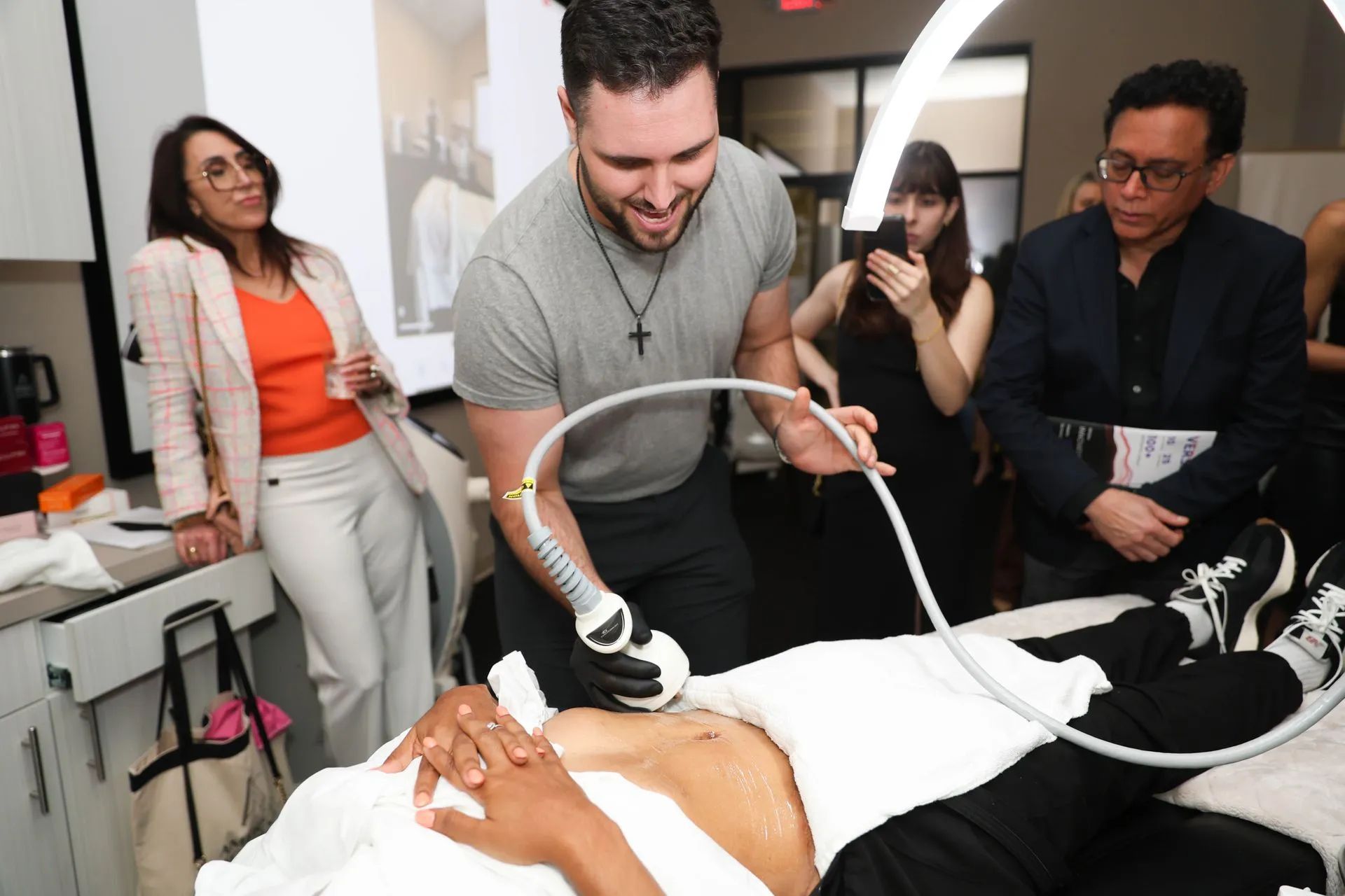 Medical staff performing a procedure on a patient while others observe in a clinical room