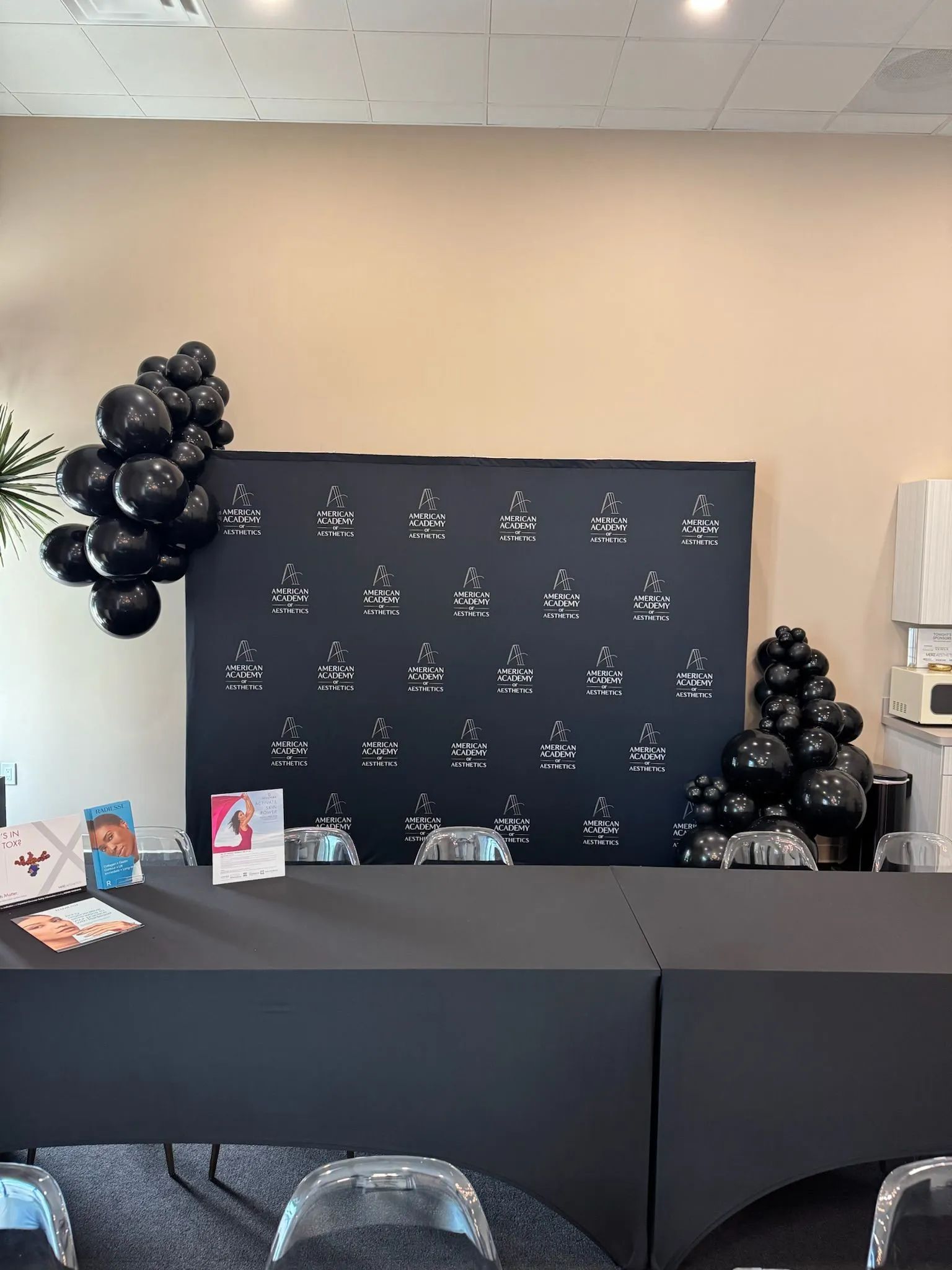 Black balloon-decorated event backdrop with a table and gift bags in front