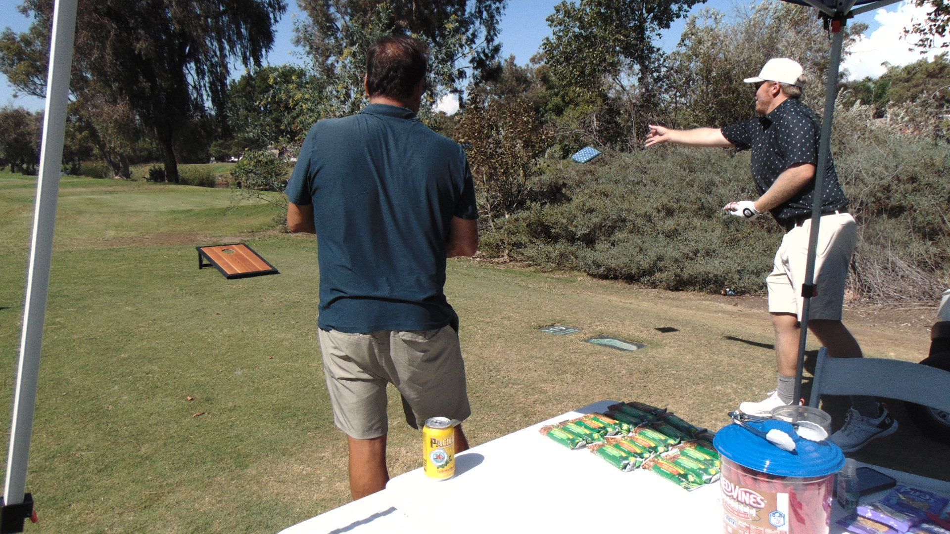 Two people standing on a golf course, one pointing toward the fairway near a tee area.