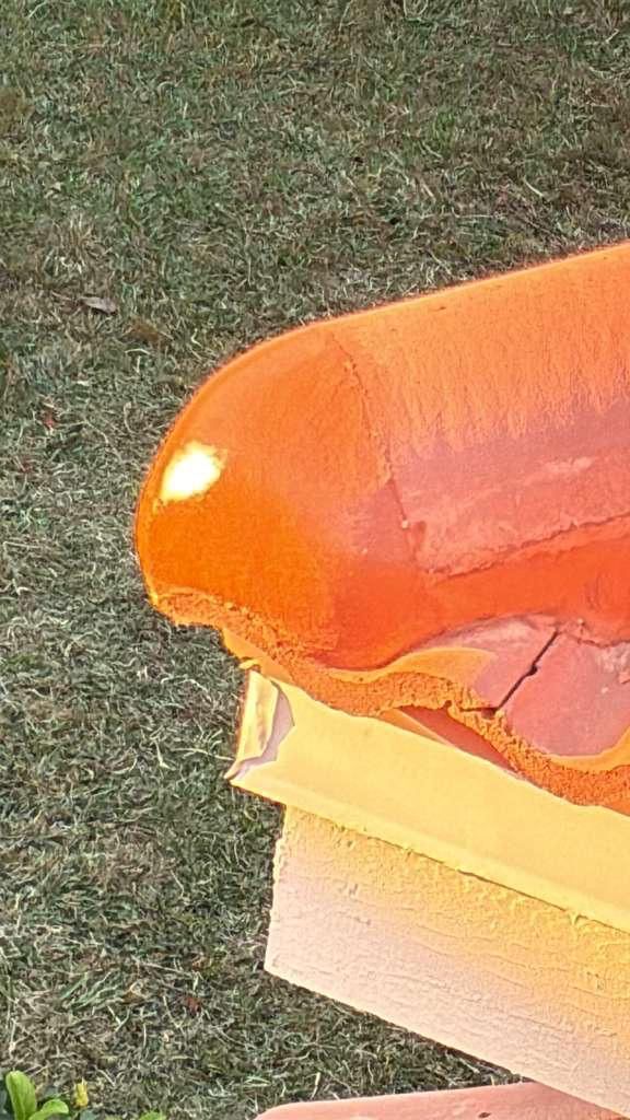 Orange and yellow painted structure on brick and grass.