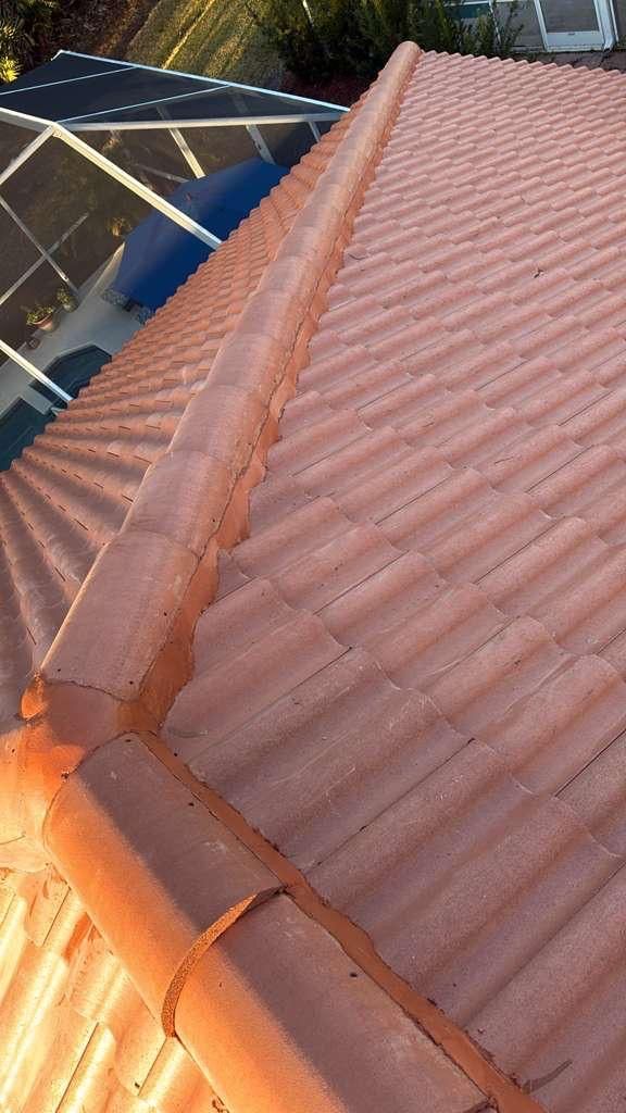 Red tile roof with a gutter, viewed at an angle with a pool screen in the background.