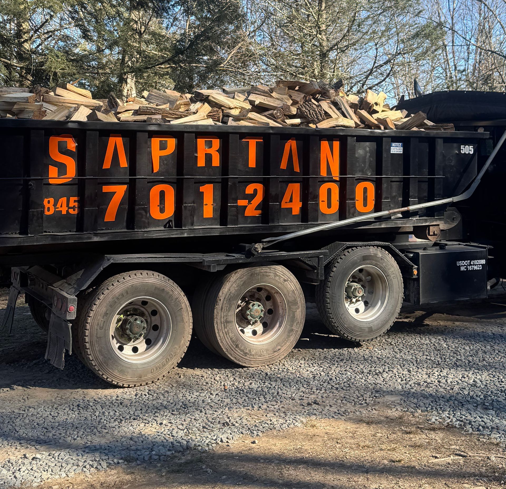 Black truck bed filled with firewood, orange lettering reading 
