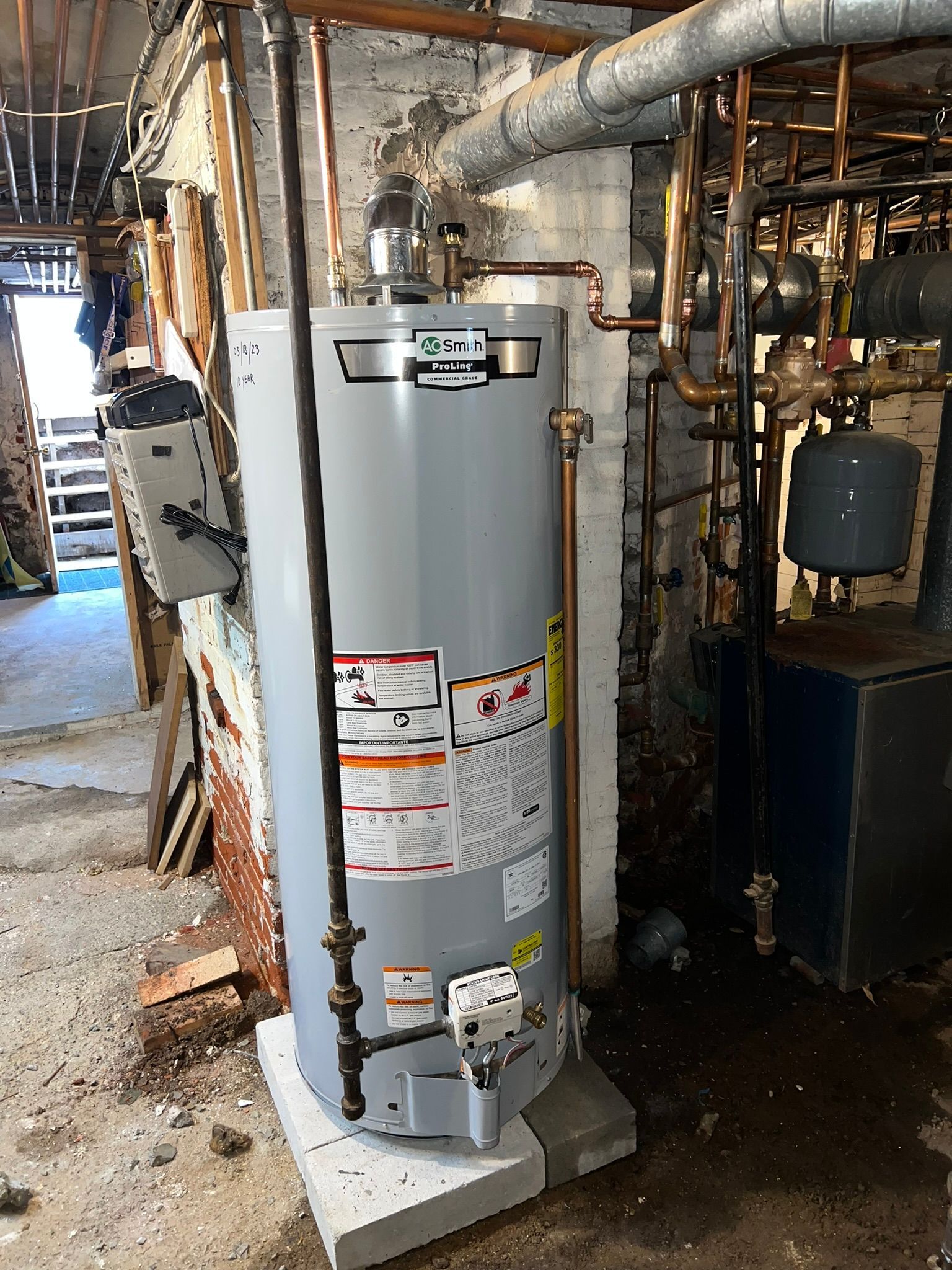 a water heater is sitting in a basement next to a brick wall