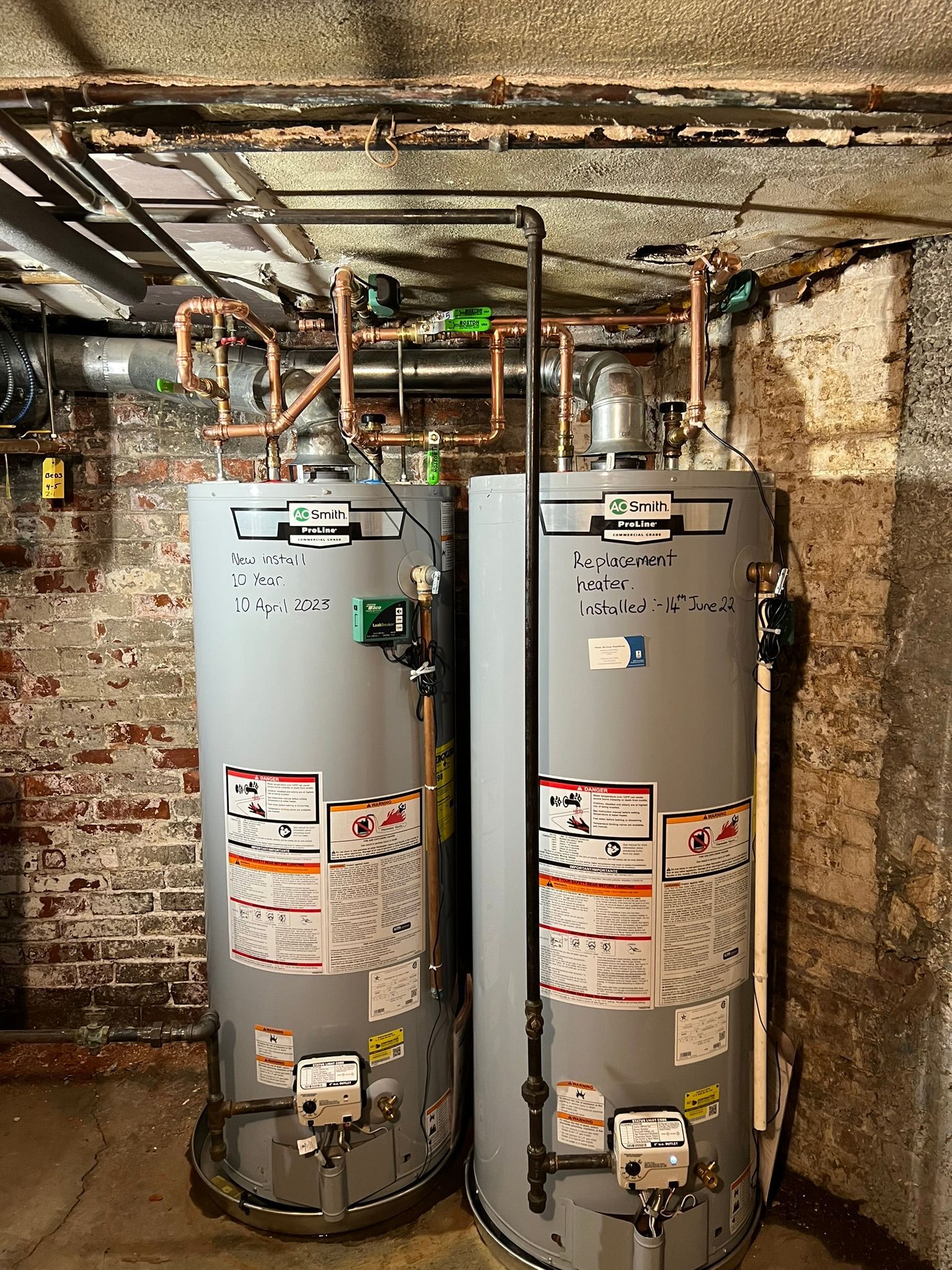 two water heaters are sitting next to each other in a basement